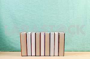 Открытая книга, стопка книг в твердом переплете на деревянном столе. Обратно в школу. Копирование пространства