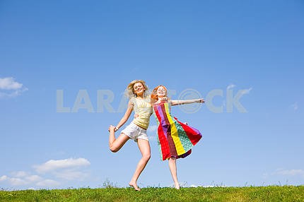 Два счастливых девочки прыгают вместе на зеленый луг .
