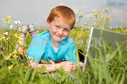 Улыбка ребенка с ноутбуком на лугу