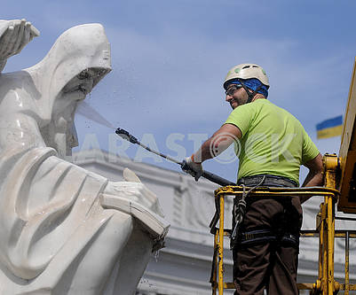 Работник клининговой компании моет памятник Кириллу и Мефодию