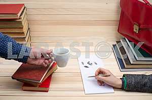 На деревянном столе книги, документы, калькулятор, красный портфель.