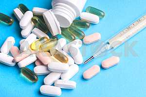 Много таблеток и таблетки, изолированные на светло синем фоне