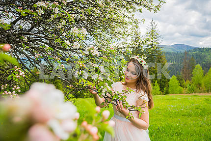 Невеста стоит рядом с цветущей яблоней,