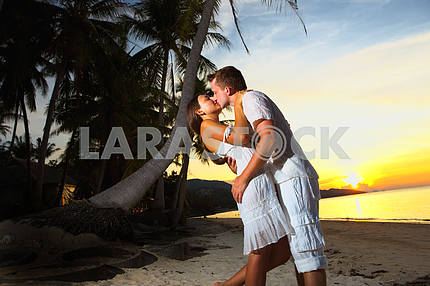 Молодая пара, обниматься на пляже на закате