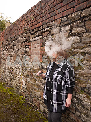 Зрелая женщина курит электронную сигарету