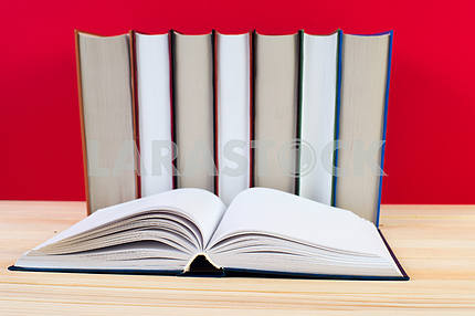 Открытая книга, стопка книг в твердом переплете на деревянном столе. Обратно в школу. Копирование пространства