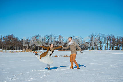 Молодая пара свадьба, играя в снегу в Солнечный зимний день. Свадьба в деревенском стиле. Милая девушка в коротком свадебном белом платье, голубое небо на заднем плане. Браун свадьба стиль. Танцы