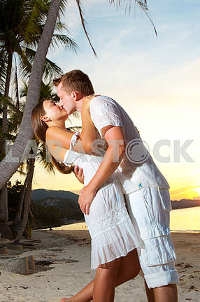 Молодая пара, обниматься на пляже на закате