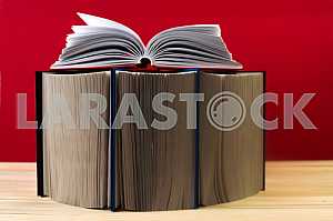 Открытая книга, стопка книг в твердом переплете на деревянном столе. Обратно в школу. Копирование пространства