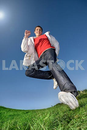 Счастливый молодой человек - прыжки конец летит в синем небе