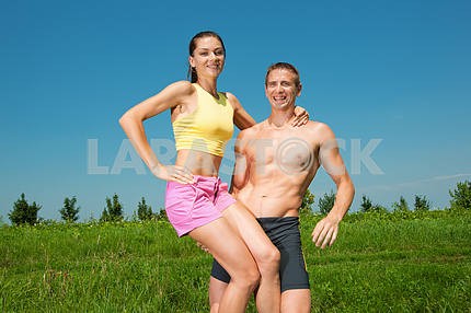 Молодая спортивная пара, улыбаясь в голубое небо
