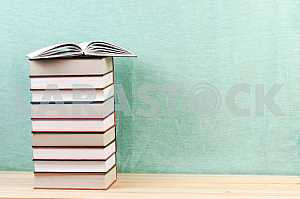 Открытая книга, стопка книг в твердом переплете на деревянном столе. Обратно в школу. Копирование пространства