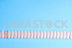 Много таблеток и таблетки, изолированные на светло синем фоне