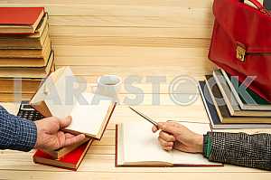 На деревянном столе книги, документы, калькулятор, красный портфель.