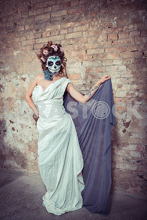 Привлекательная молодая женщина с сахаром череп макияж. Красивая женщина в макияж традиционный мексиканский Calavera черепа Катрины, стоя возле старой кирпичной стены с розами в волосах