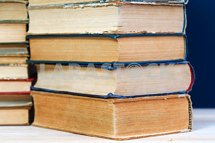 Открытая книга, стопка книг в твердом переплете на деревянном столе. Обратно в школу. Копирование пространства