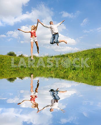 Счастливый молодая пара - прыжки в небо над зеленый луг