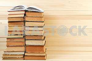Открытая книга, стопка книг в твердом переплете на деревянном столе. Обратно в школу. Копирование пространства