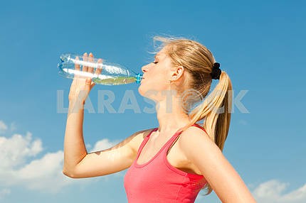 Красивая девушка питьевой воды против голубого неба