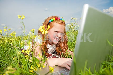 Девушка с ноутбуком отдыхает на лугу .