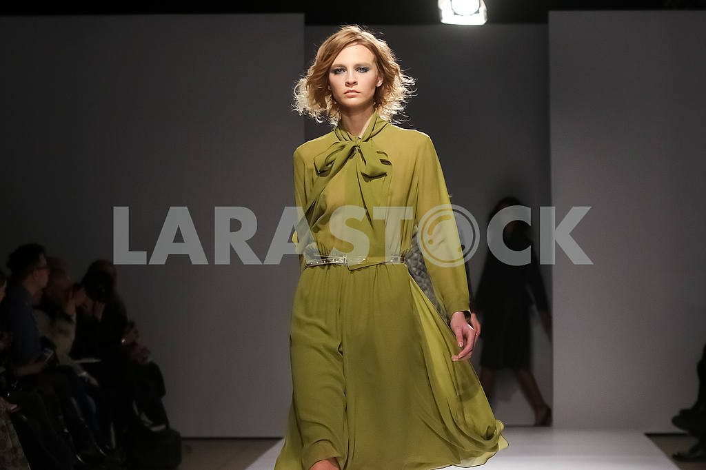 A model in an olive dress. Display by V by Gres — Image 51220