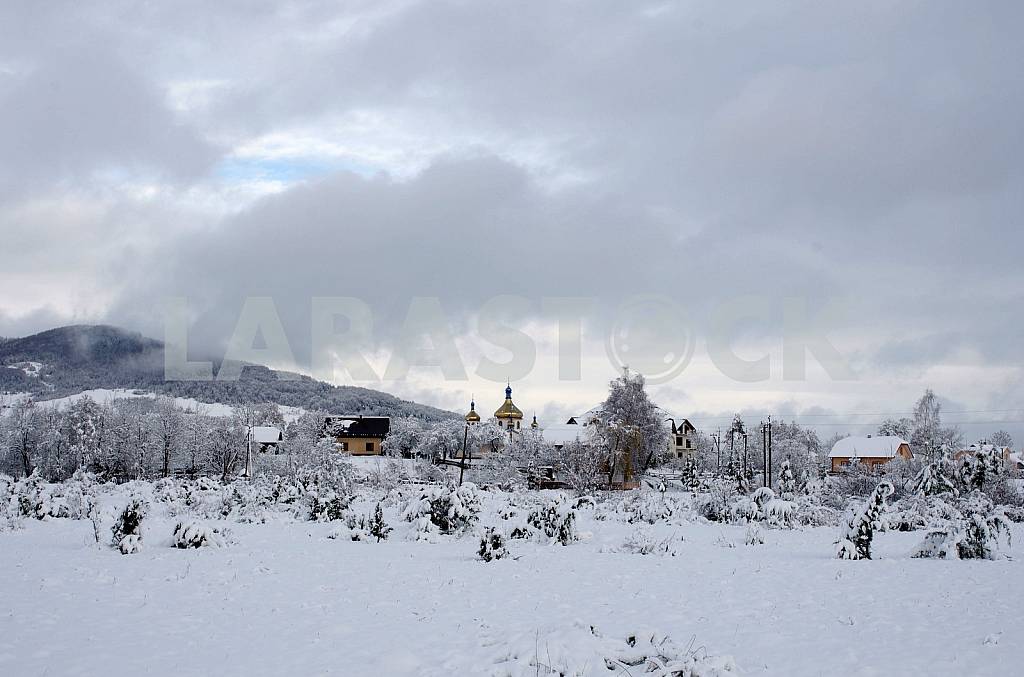Зимний пейзаж. Заснеженный поселок с домами и церковью на фоне гор. — Изображение 45140