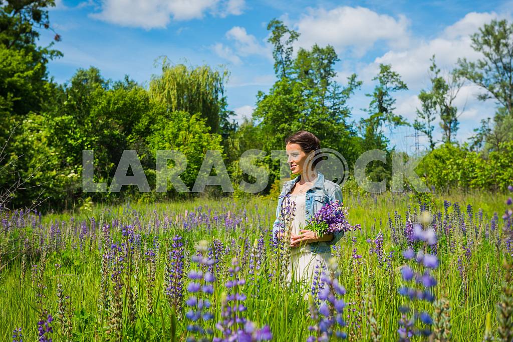 Young woman, happy, standing among the field of violet lupines, purple flowers. Blue sky on the background. Summer, sunny day! — Image 31250
