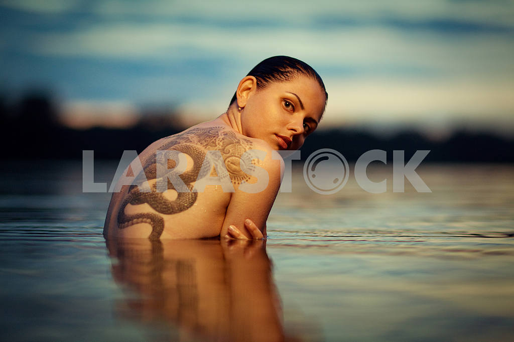 Young tattooing girl swiming in sea waves. An art photo. A beaut — Image 6460