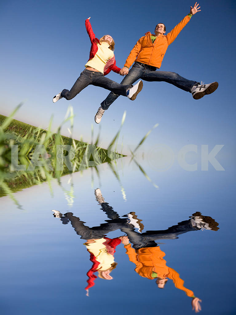 Счастливая пара улыбаясь прыжки в голубое небо — Изображение 6823