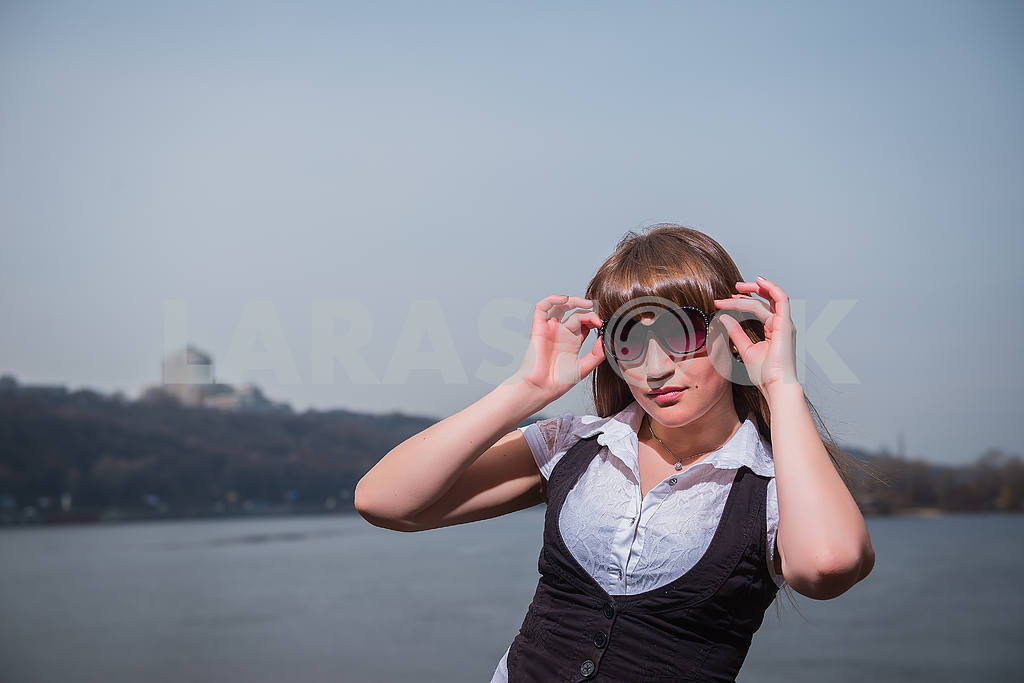 Girl with sunglases Women holding the sunglasses with light brown hair, dressed in white and black, portrait, sunny day, with river and the city on the background — Image 29166