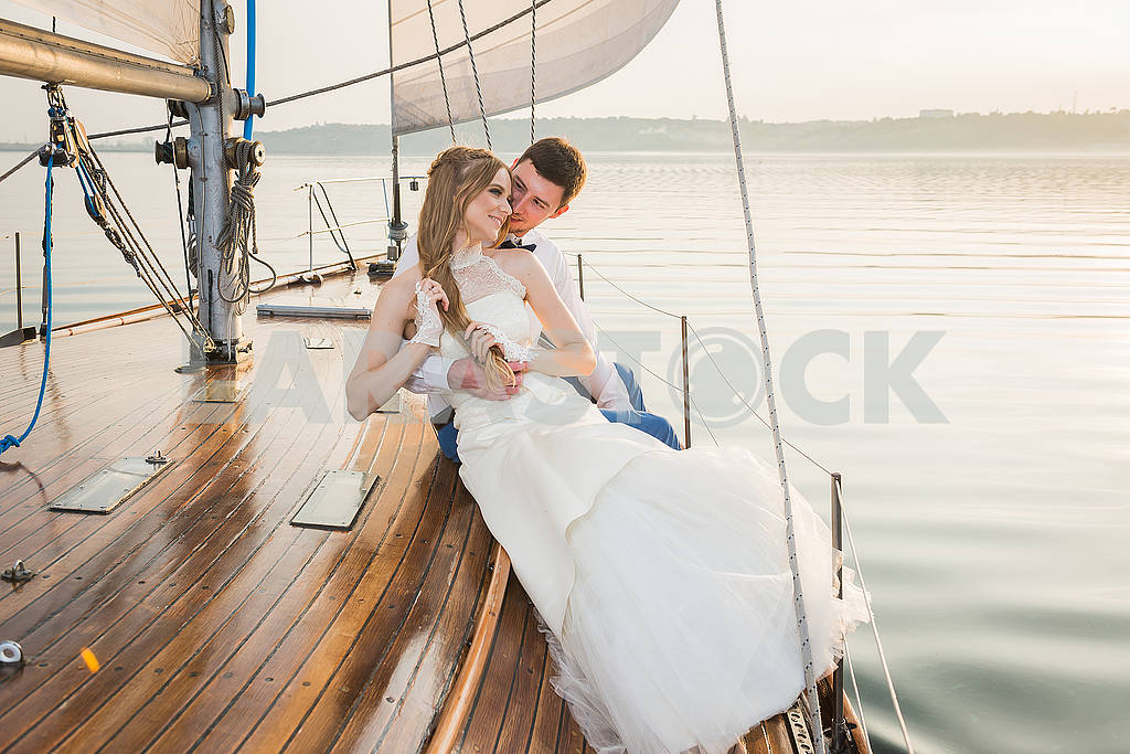 Happy bride and groom hugging on a yacht - looking into each other evening yellow sun — Image 50508