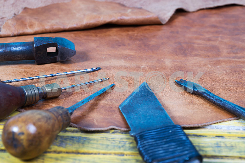 Leather craft tools on a wooden background. Leather craftmans work desk . Piece of hide and working handmade tools on a work table — Image 46188