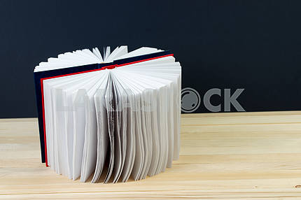Open book, stack of hardback books on wooden table. Back to school. Copy space