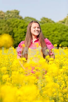 Pretty smiling girl relaxing on green meadow full of flowers. So