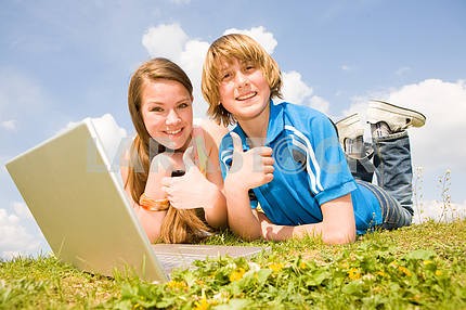 Два улыбается подростков с ноутбуком отдыхает на лугу .