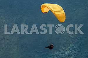 Paraglider flying over mountains on a summer day