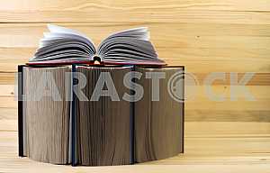 Открытая книга, стопка книг в твердом переплете на деревянном столе. Обратно в школу. Копирование пространства