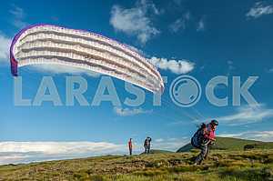 Paraglider flying over mountains on a summer day