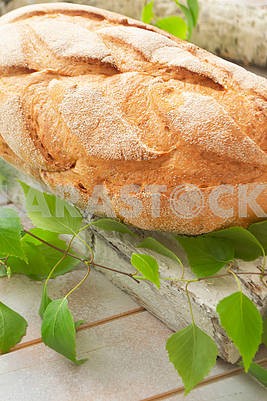 Fresh and delicious bread on wooden shabby cutting board and birch branch for healthy diet background