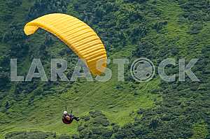 Paraglider flying over mountains on a summer day