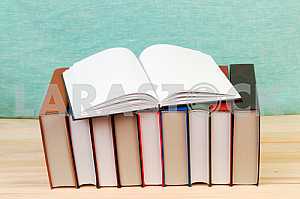 Open book, stack of hardback books on wooden table. Back to school. Copy space