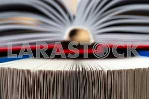 Открытая книга, стопка книг в твердом переплете на деревянном столе. Обратно в школу. Копирование пространства