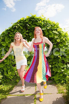 Two happy young women are runing in a park