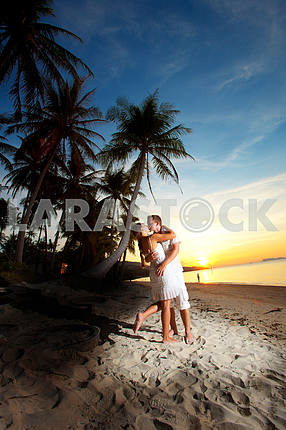 молодая пара, обниматься на пляже на закате
