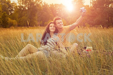young fashion beautiful loving casual style couple  lying down on floral field in autumnal park, warm sunny day, enjoying family, romantic date, happiness and love concept.