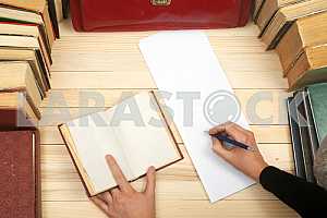 On a wooden table books, documents, calculator, red briefcase.
