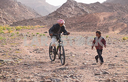 Мальчики бедуины катаются на велосипеде																				