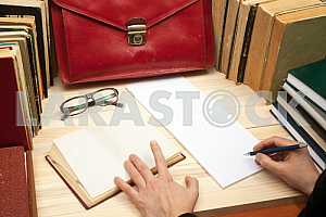 On a wooden table books, documents, calculator, red briefcase.