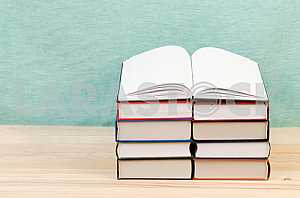 Открытая книга, стопка книг в твердом переплете на деревянном столе. Обратно в школу. Копирование пространства