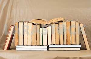Old and used hardback books or text books on wooden table. Books and reading are essential for self improvement, gaining knowledge and success in our careers, business and personal lives. Copy space